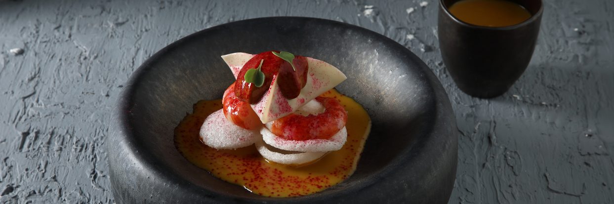 Aromatic pumpkin soup with shrimp and black garlic foam
